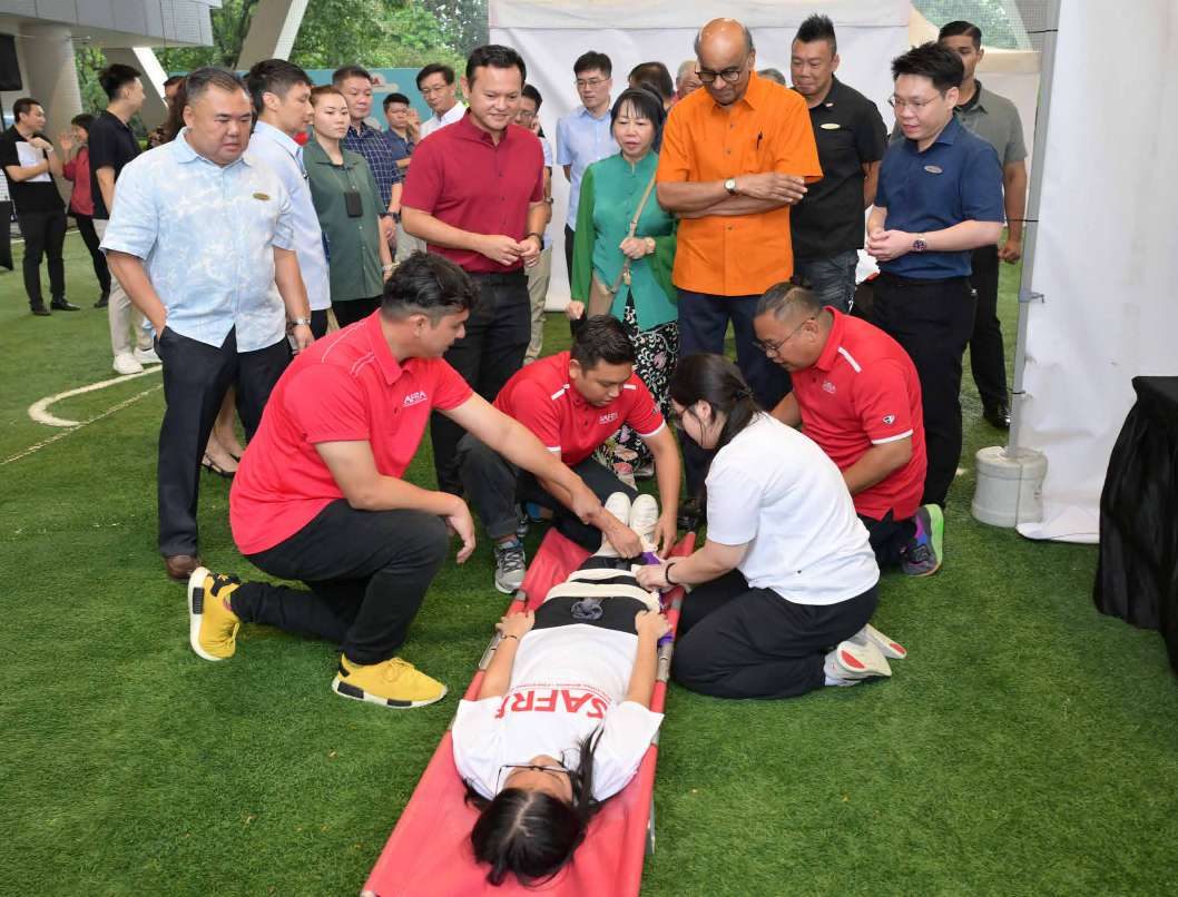 President Tharman Shanmugaratnam and SAFRA leaders observing a first-aid demonstration on grass at the Be@SAFRA Open House.